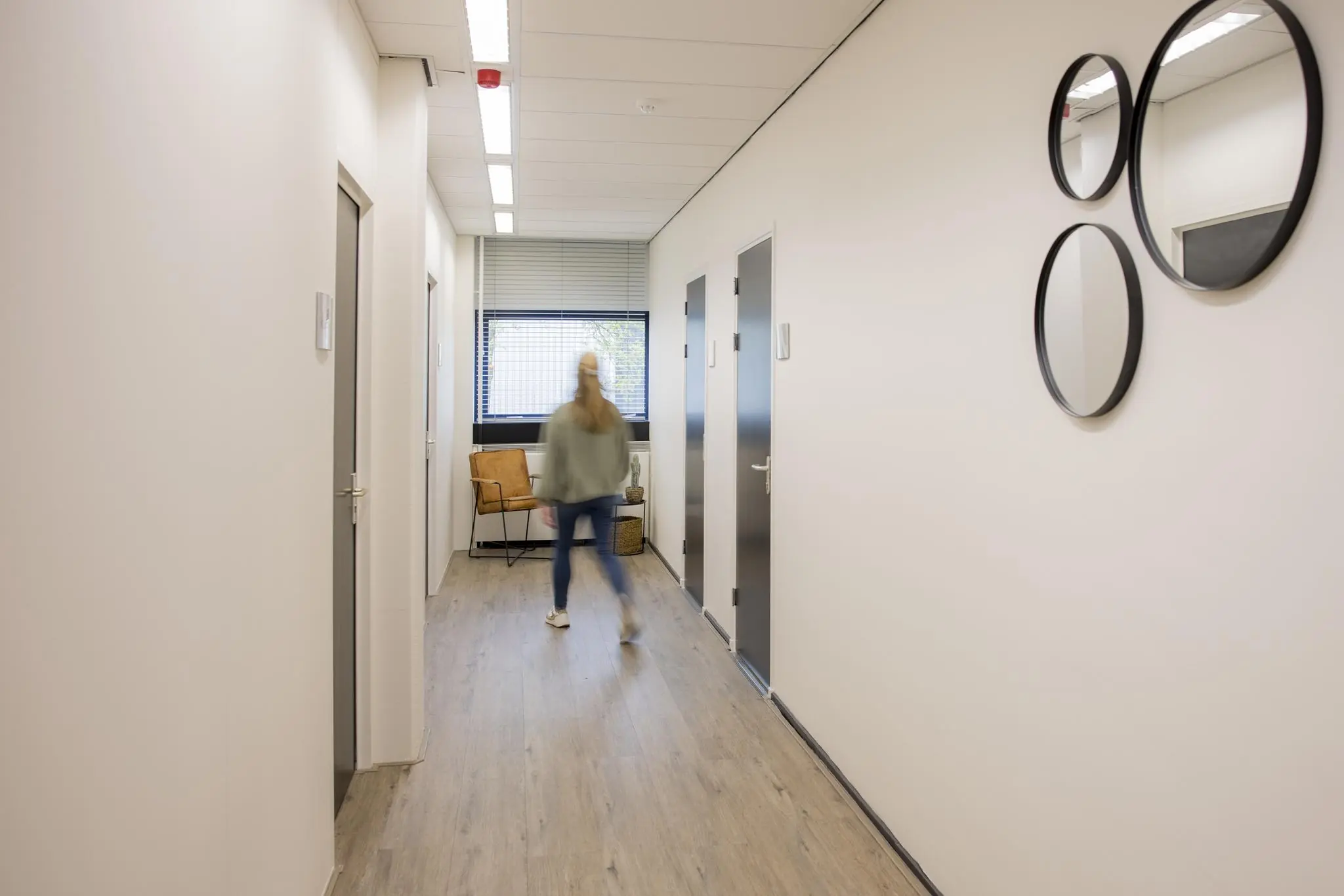 Een persoon loopt door een lichte gang met meerdere deuren in een kantoor aan de Markerkant 13.